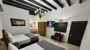 Habitación de hotel con dos camas, un armario de madera, un televisor y una puerta.
