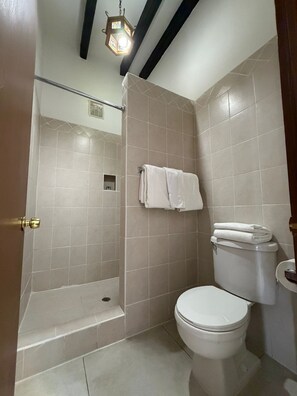 A bathroom with a shower, toilet, and a towel rack. - Hotel Cosmos Don Carlos (Mexicali)