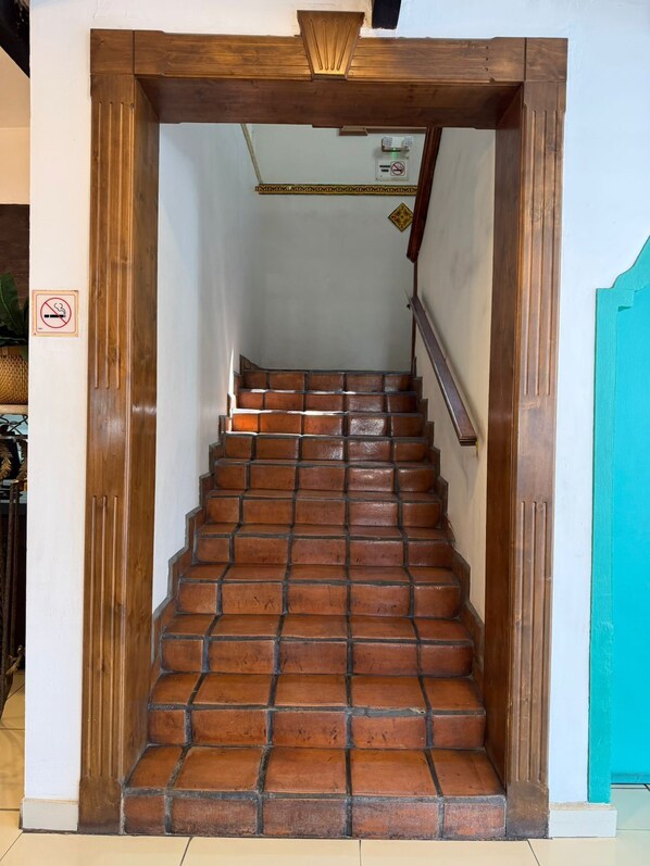 A wooden staircase with a handrail, leading to a room with a white wall and a teal door.