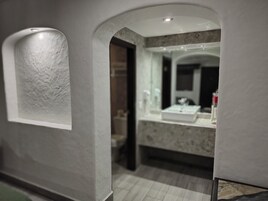 Een moderne badkamer met een marmeren aanrechtblad, een spiegel en een inbouw plafondlamp.