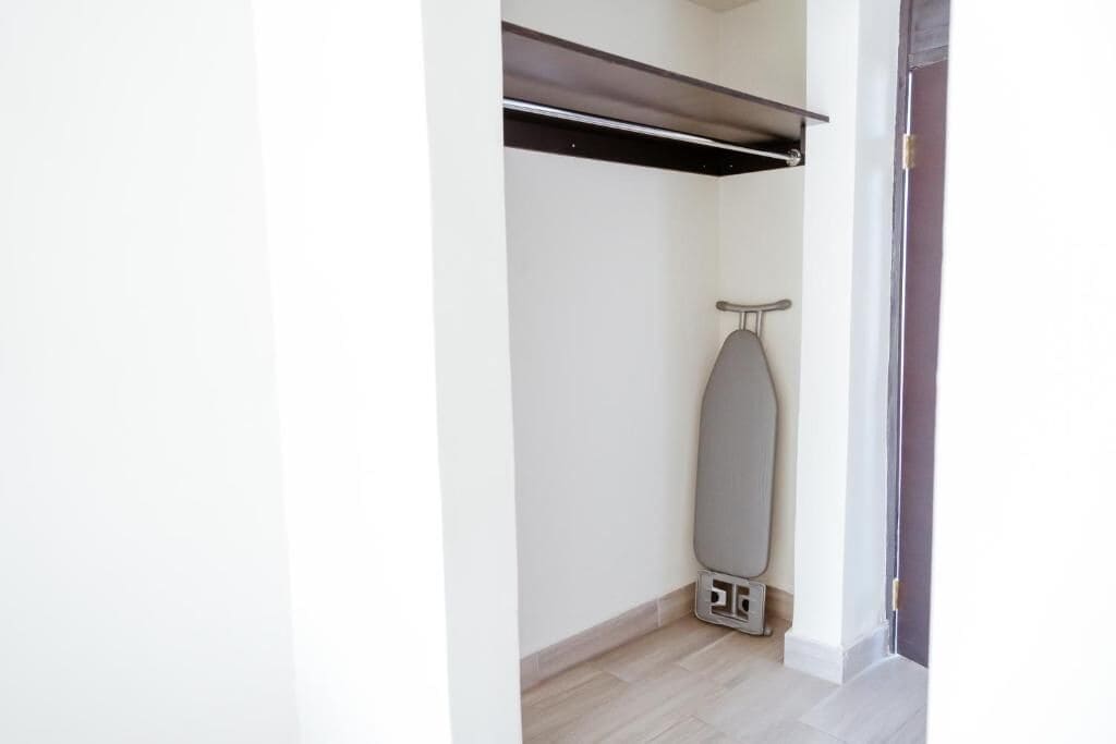 A corner of a room with a wall-mounted ironing board and a power outlet.