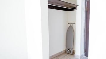 A corner of a room with a wall-mounted ironing board and a power outlet.