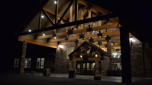 A large building with a prominent wooden structure and stone walls, featuring multiple windows and a well-lit entrance. - Canyon Country Lodge (Escalante)
