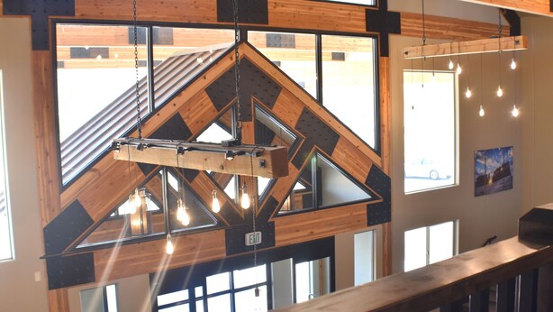 A modern interior with a wooden ceiling structure, large windows, and hanging light fixtures. - Canyon Country Lodge (Escalante)