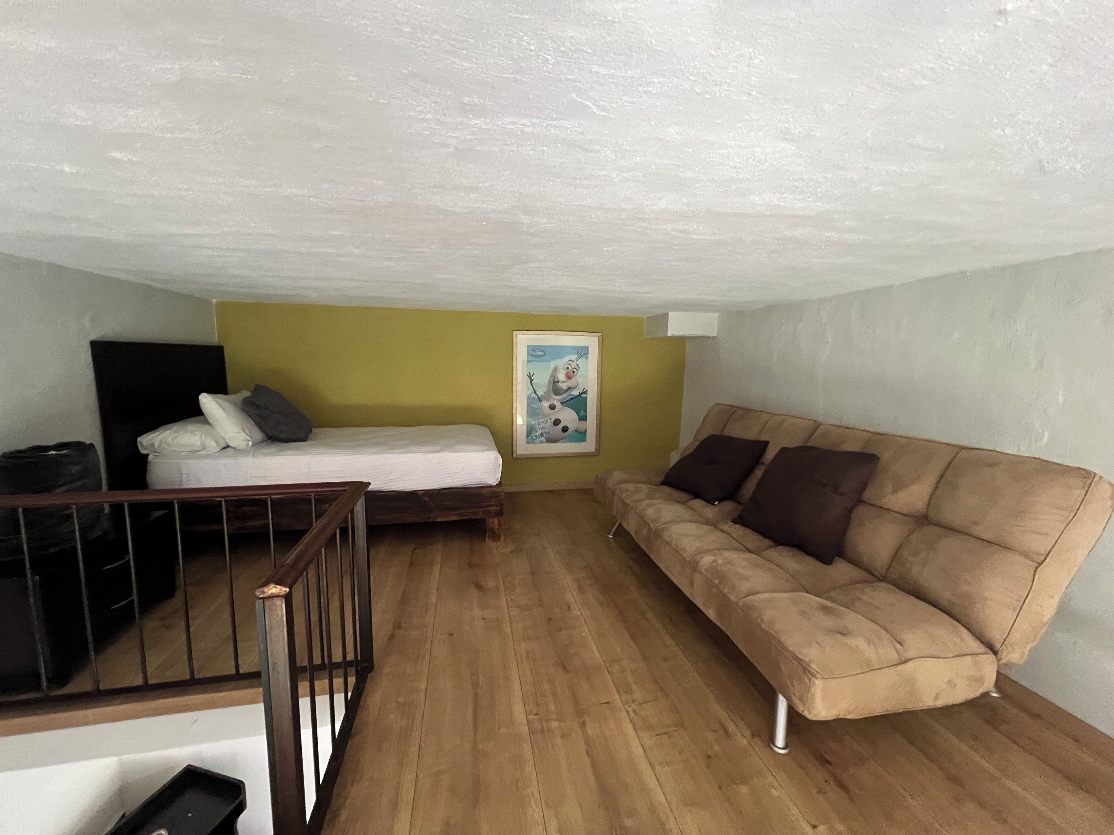 Une petite pièce agréable, dotée d’un lit, d’un canapé et d’un plancher en bois.
