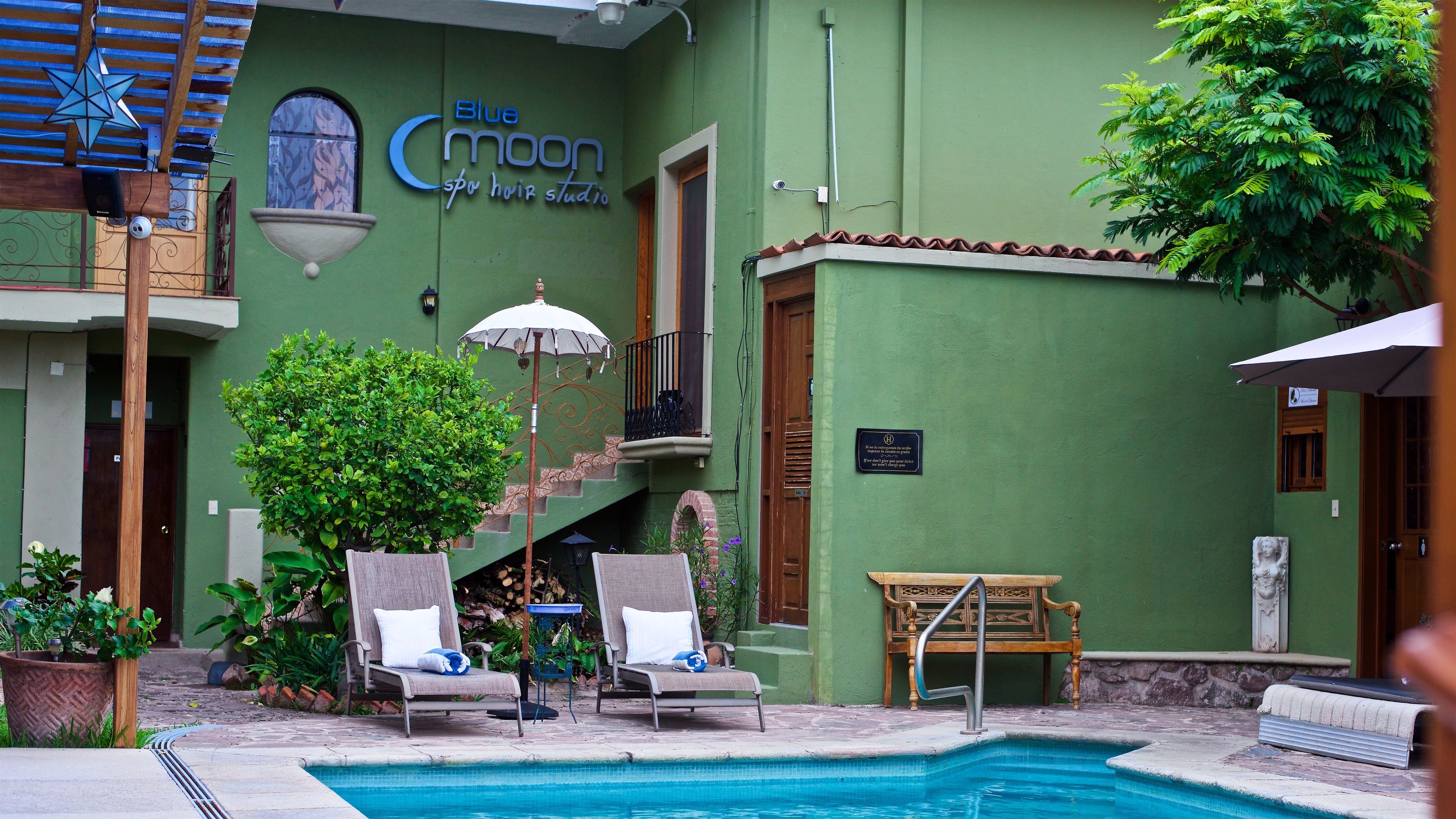 A spa with a pool, a wooden bench, and two lounge chairs.