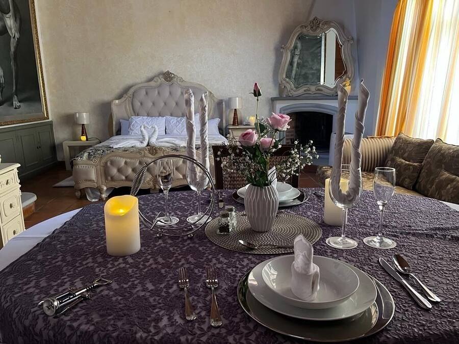 Una mesa de comedor elegantemente dispuesta, con una vela, un florero y un espejo encima.