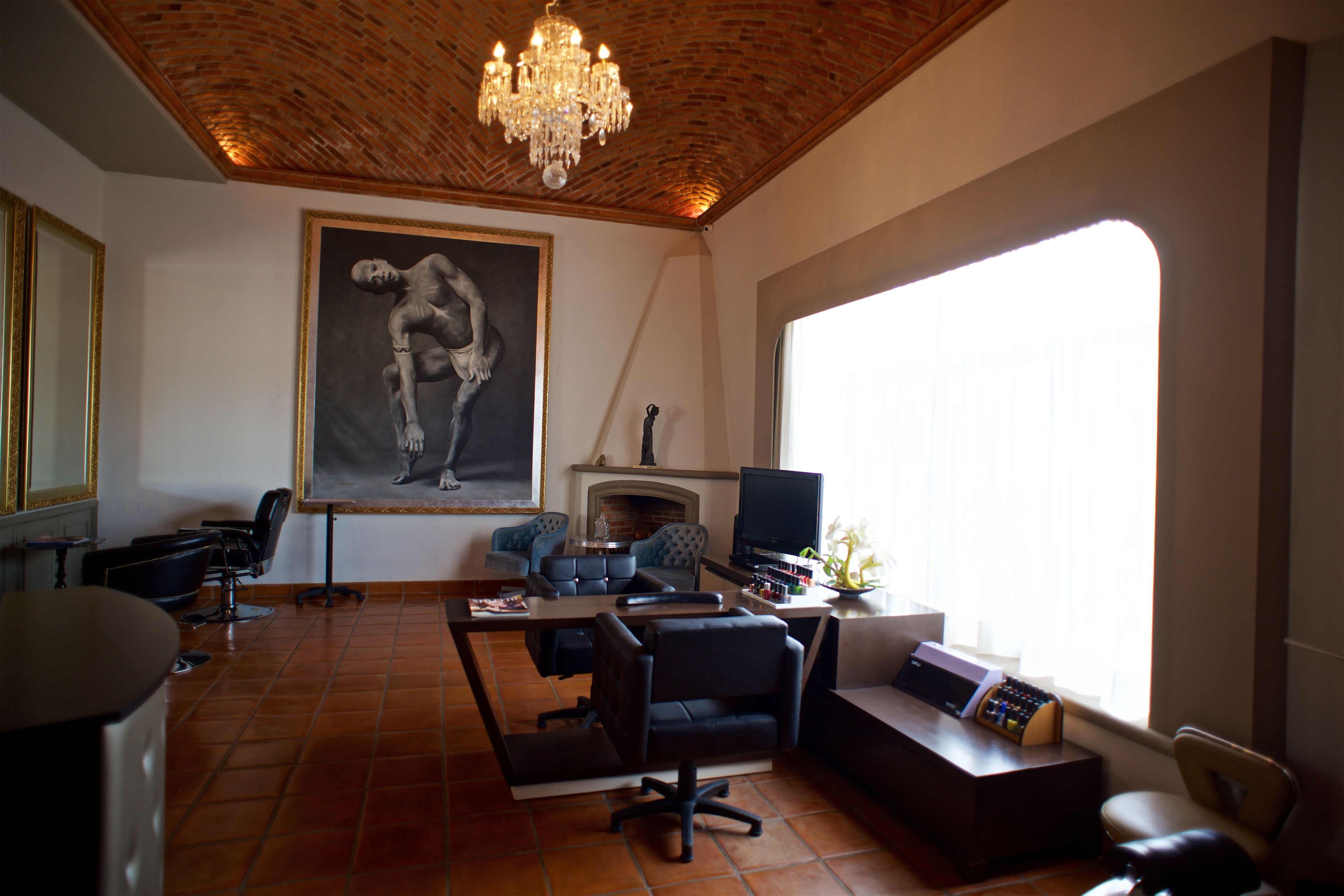 Una sala de estar con chimenea, un cuadro grande, un televisor y un escritorio con computadora.