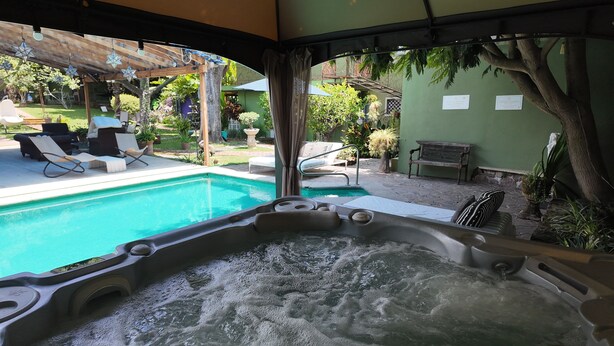 A hot tub with a view of a swimming pool and outdoor seating area. - Hacienda del Lago Boutique Hotel (Ajijic)