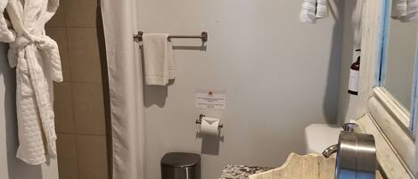 Un baño con ducha, inodoro, lavabo y toallero.