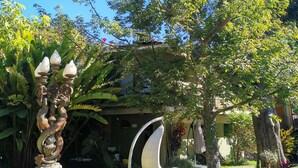 A garden with a decorative fountain, a hanging chair, and a tree with white flowers. - Hacienda del Lago Boutique Hotel (Ajijic)