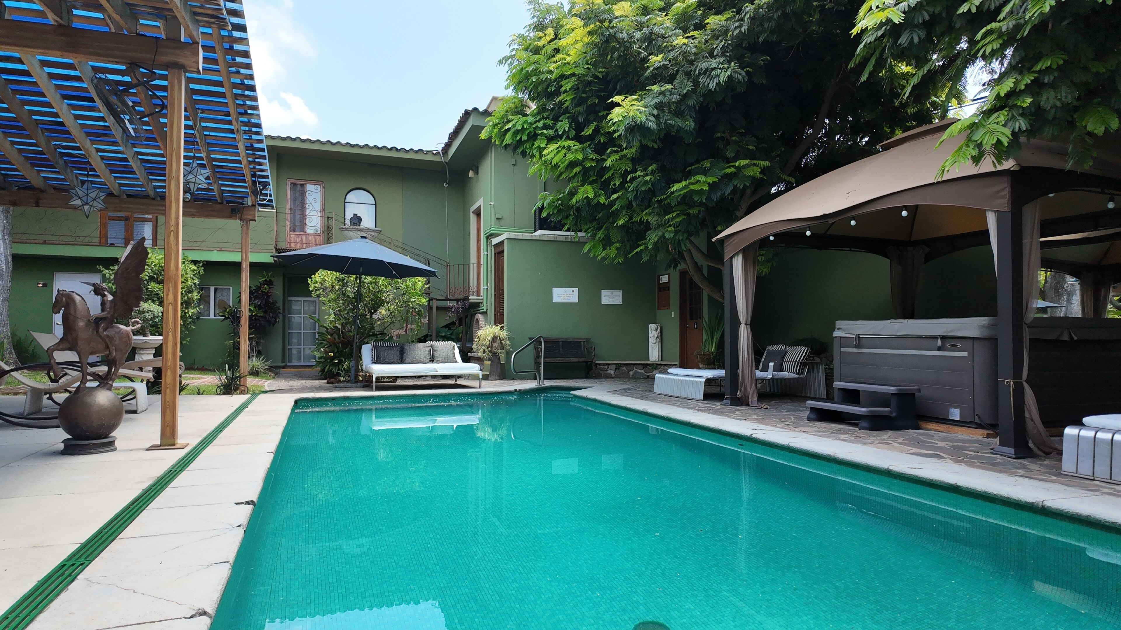 A swimming pool with lounge chairs and a covered seating area.