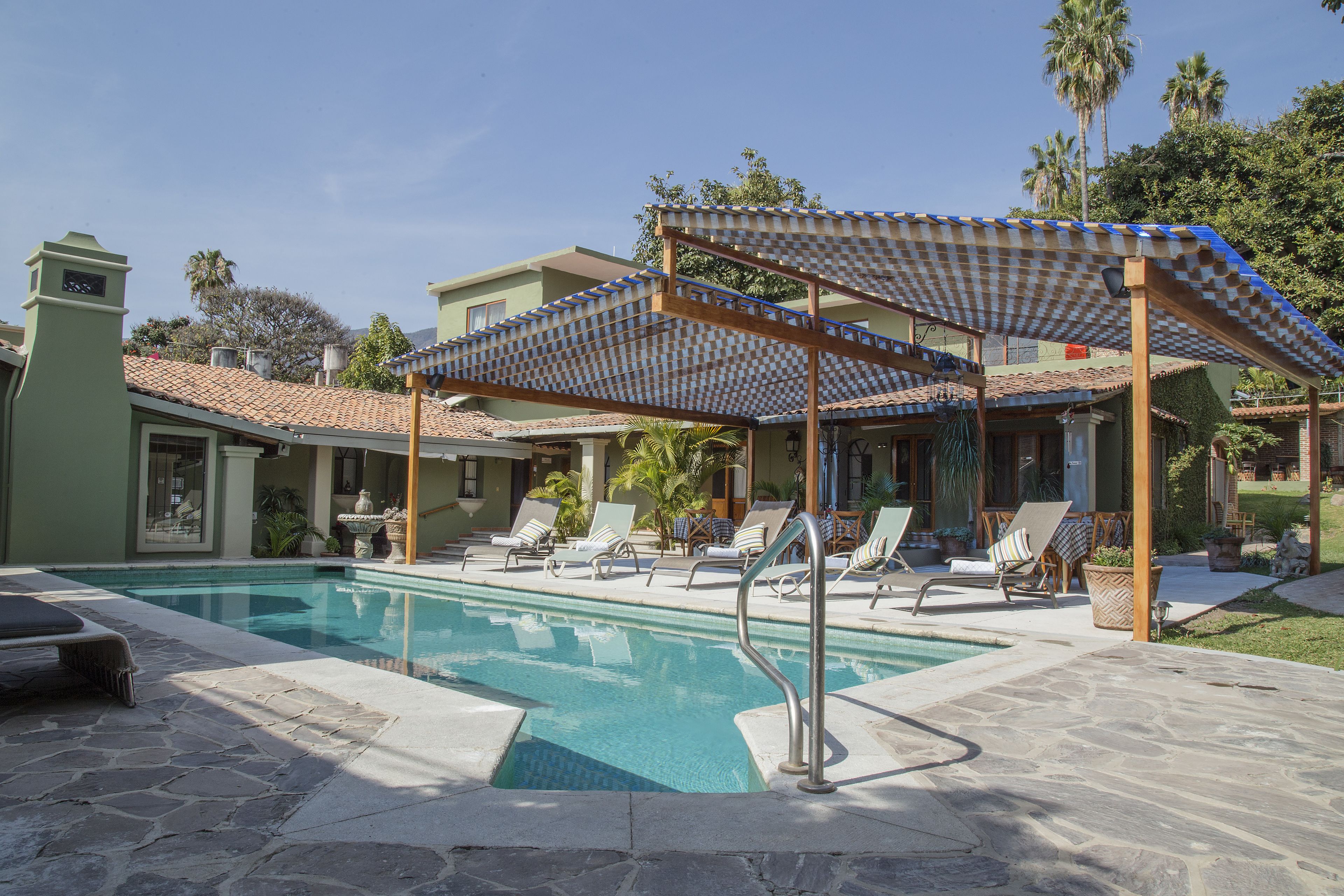 Un área de piscina con sillas de descanso y una pérgola.