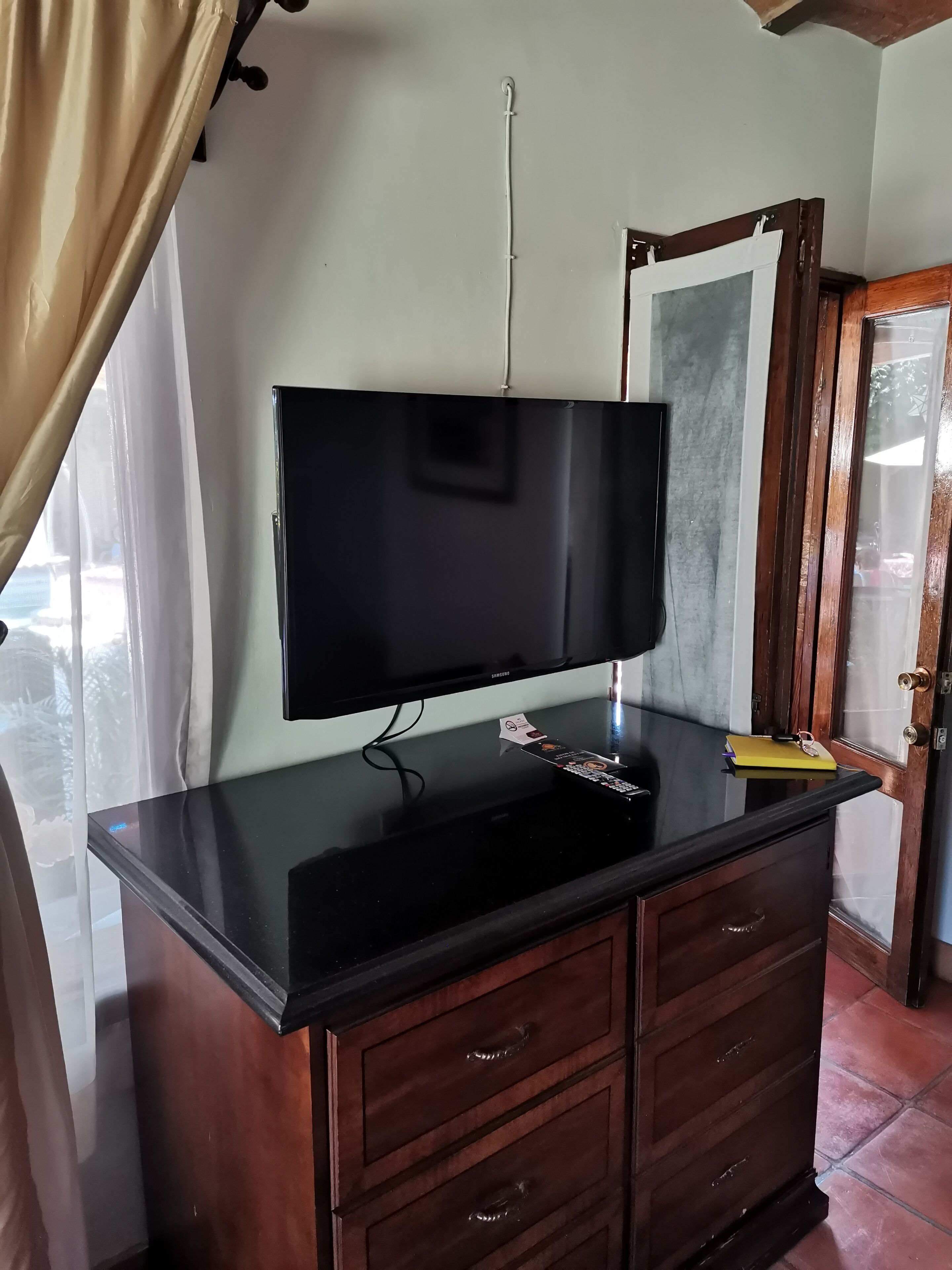 A flat-screen TV mounted on a black countertop, wooden cabinets below, and a door with a glass panel to the right.