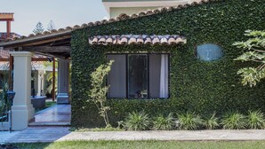 A building with a green ivy-covered exterior, a tiled roof, and a visible window with a view of the interior. - Hacienda del Lago Boutique Hotel (Ajijic)