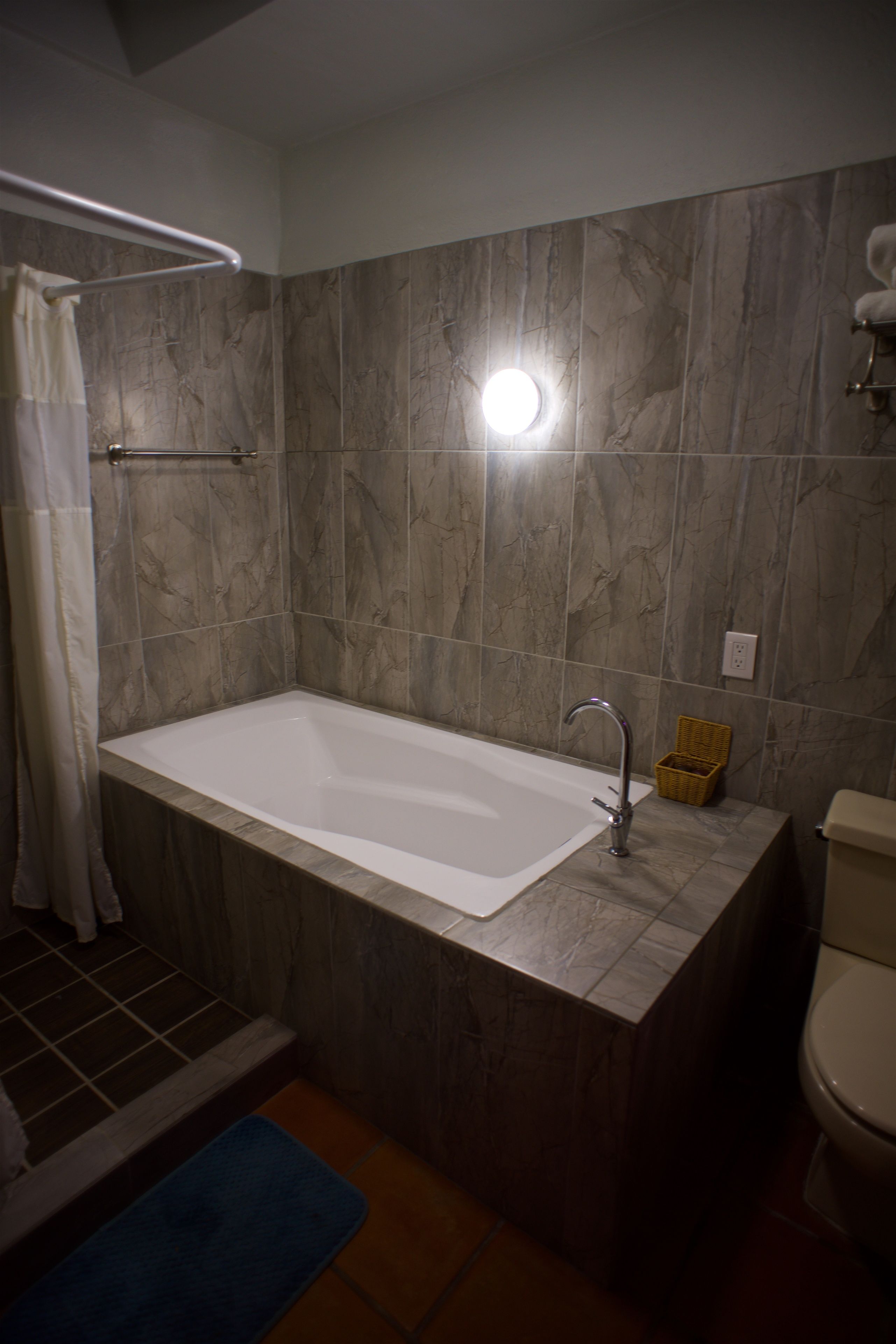 A bathroom with a bathtub, a toilet, and a shower curtain.