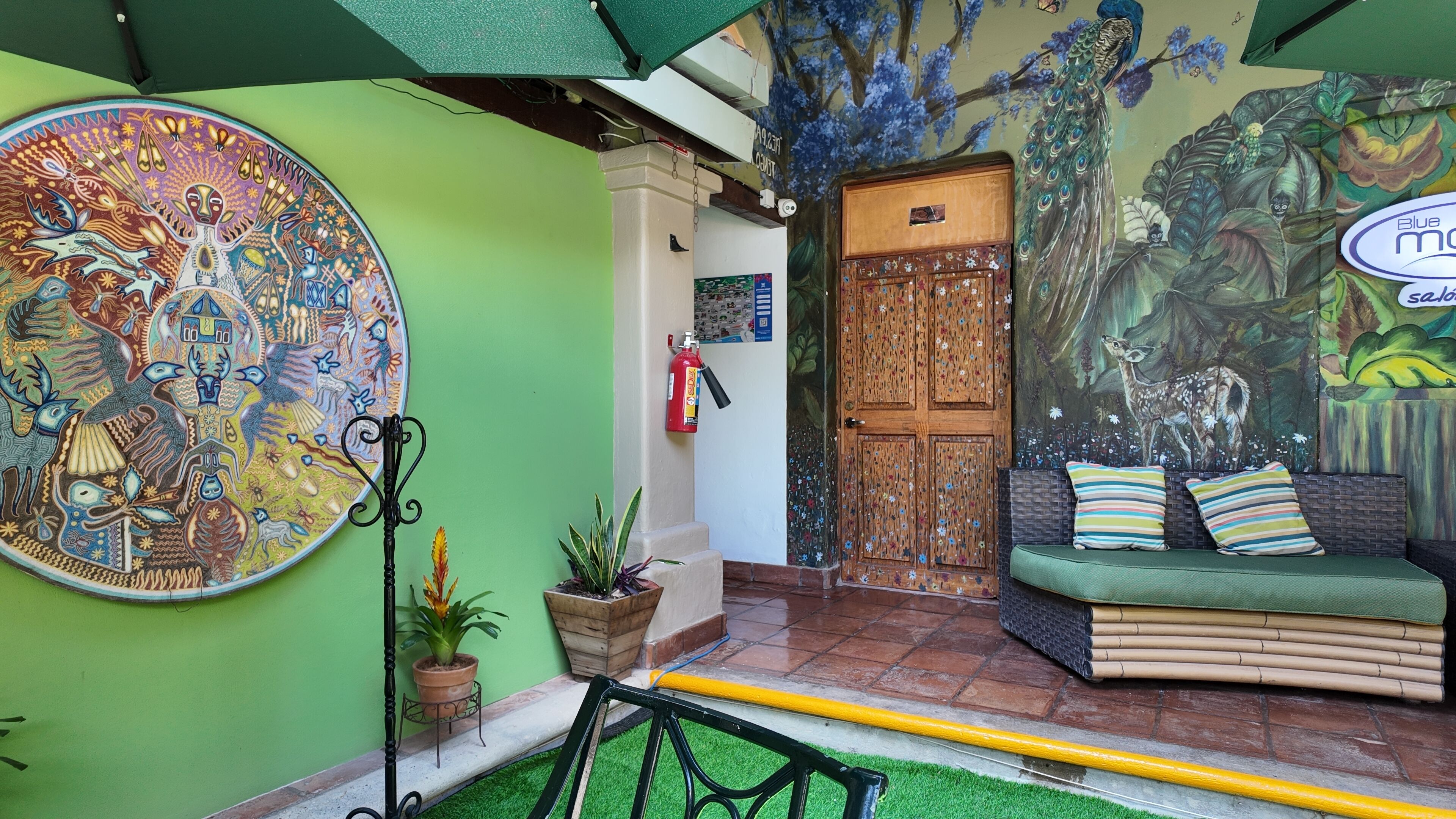 A cozy interior with a vibrant mural, a wooden door, and a green sofa with striped pillows.