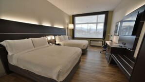 Hotellihuone, jossa on kaksi sänkyä, työpöytä, televisio ja suuri ikkuna.