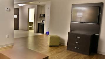 Una sala de estar moderna con un televisor de pantalla plana, una mesa de centro de madera y un otomano estampado.