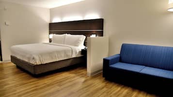 Una habitación de hotel moderna con una cama, un sofá azul y suelo de madera.