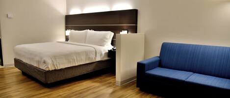 Una habitación de hotel moderna con una cama, un sofá azul y suelo de madera.