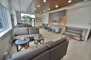 Un espace d’attente moderne, doté de canapés, de fauteuils et de tables.