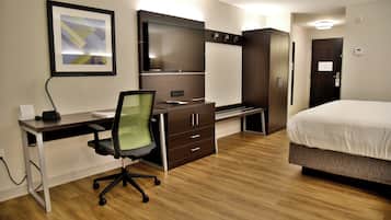 A hotel room with a bed, a desk with a chair, a wardrobe, and a television.