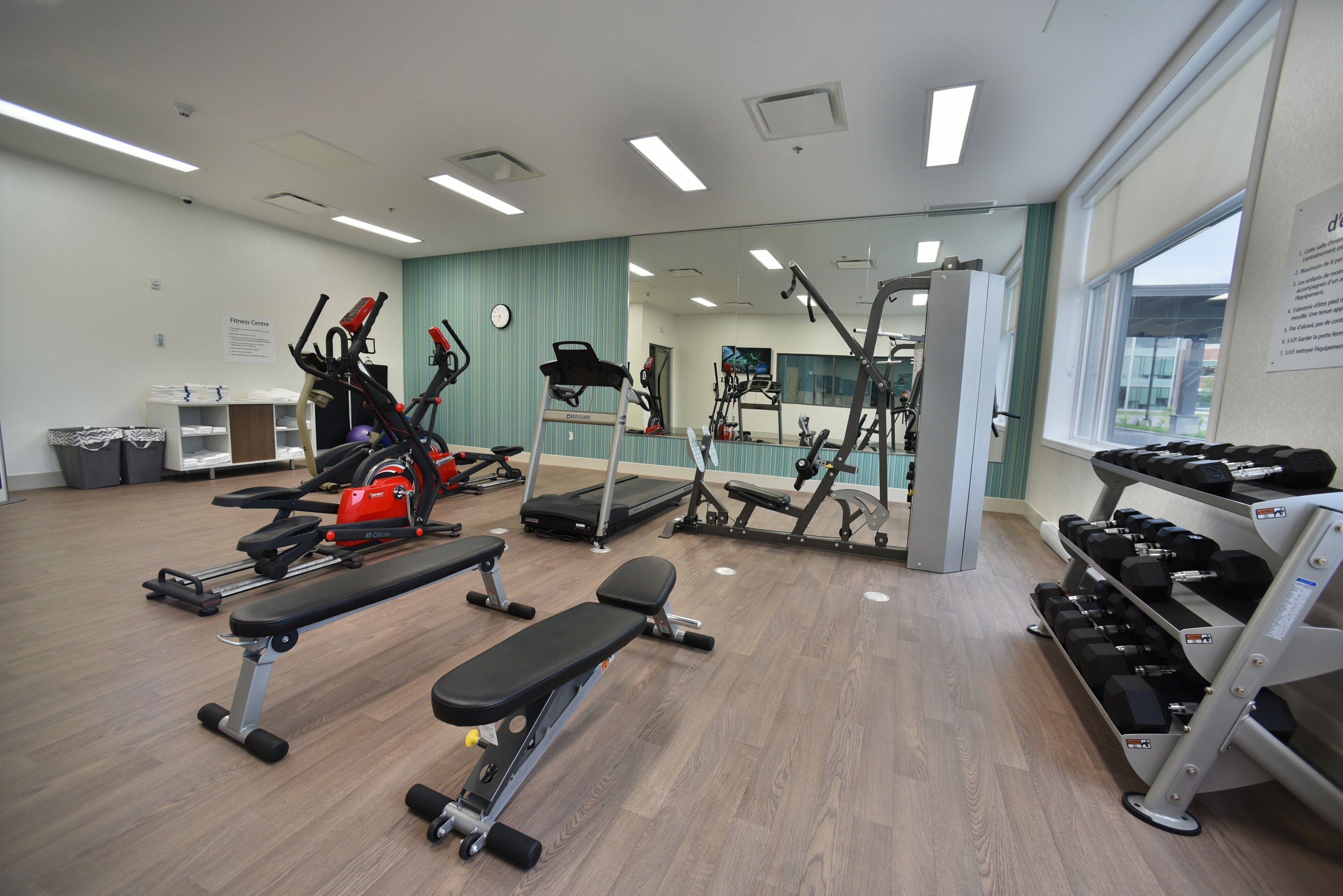 A gym with various exercise equipment, including treadmills, stationary bikes, and free weights.