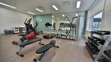 A gym with various exercise equipment, including treadmills, stationary bikes, and free weights.
