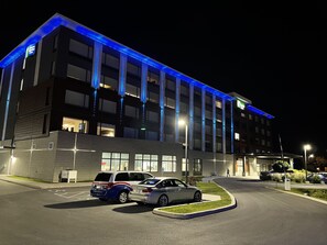 A modern hotel building with a parking lot, featuring a blue-lit facade and multiple floors. - Holiday Inn Express & Suites - Gatineau - Ottawa by IHG (Gatineau)