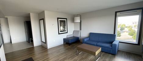 A modern living room with a blue sofa, a coffee table, and a framed picture on the wall.