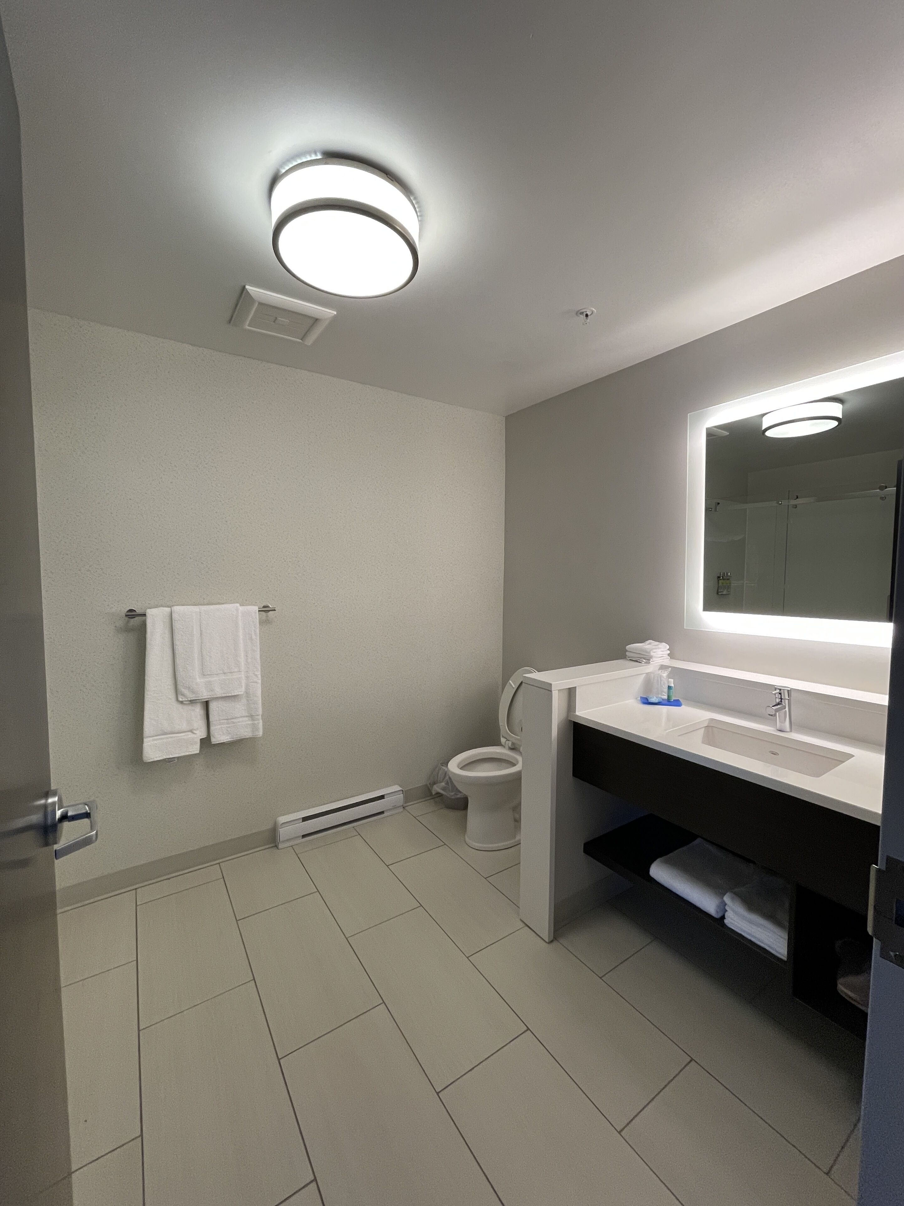 Un baño moderno con inodoro, lavamanos y espejo.