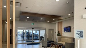 Hotellin aula, jossa on vastaanottotiski, oleskelualue ja lasiovista sisäänkäynti.