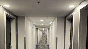 A hotel hallway with carpeted floors, doors on both sides, and a ceiling with recessed lighting. - Holiday Inn Express & Suites - Gatineau - Ottawa by IHG (Gatineau)
