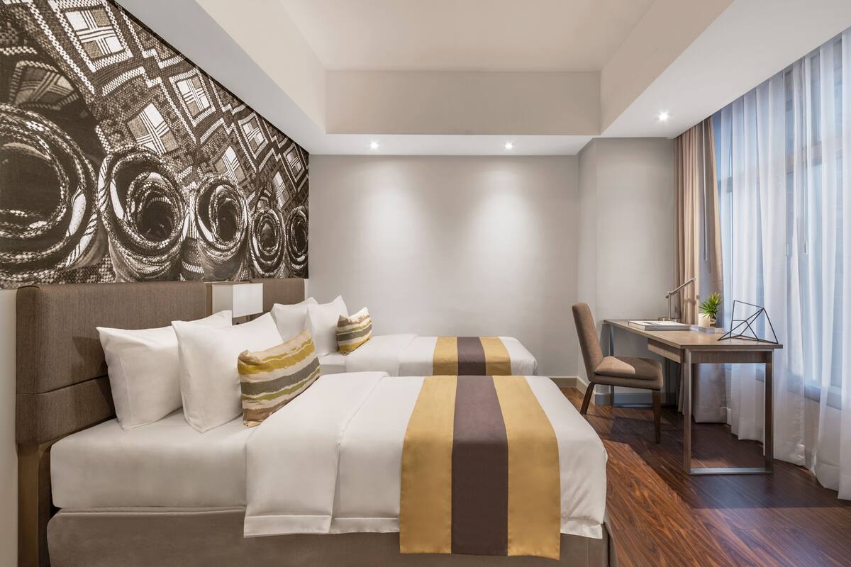 A modern hotel room with a large bed, a desk, and a chair.