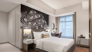 Une chambre d’hôtel moderne, dotée d’un grand lit, d’un bureau, d’une chaise et d’une grande œuvre d’art abstraite accrochée au mur.