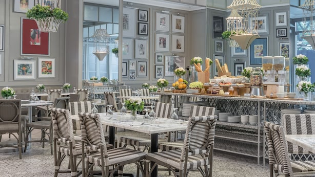 Un restaurant avec des meubles en osier, des tableaux encadrés aux murs et des luminaires suspendus.