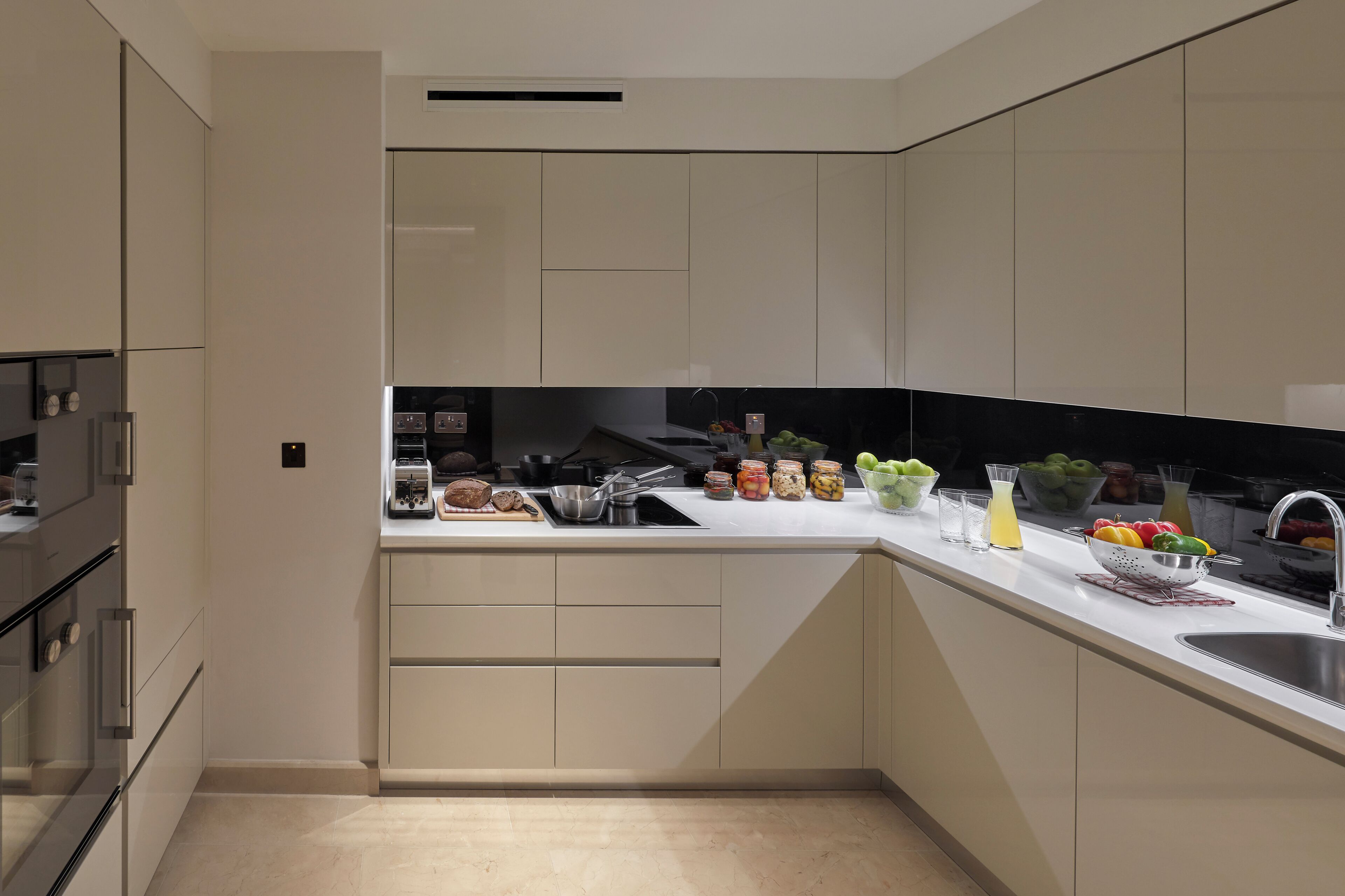 A modern kitchen with built-in appliances, a sink, and a countertop with various food items and containers.