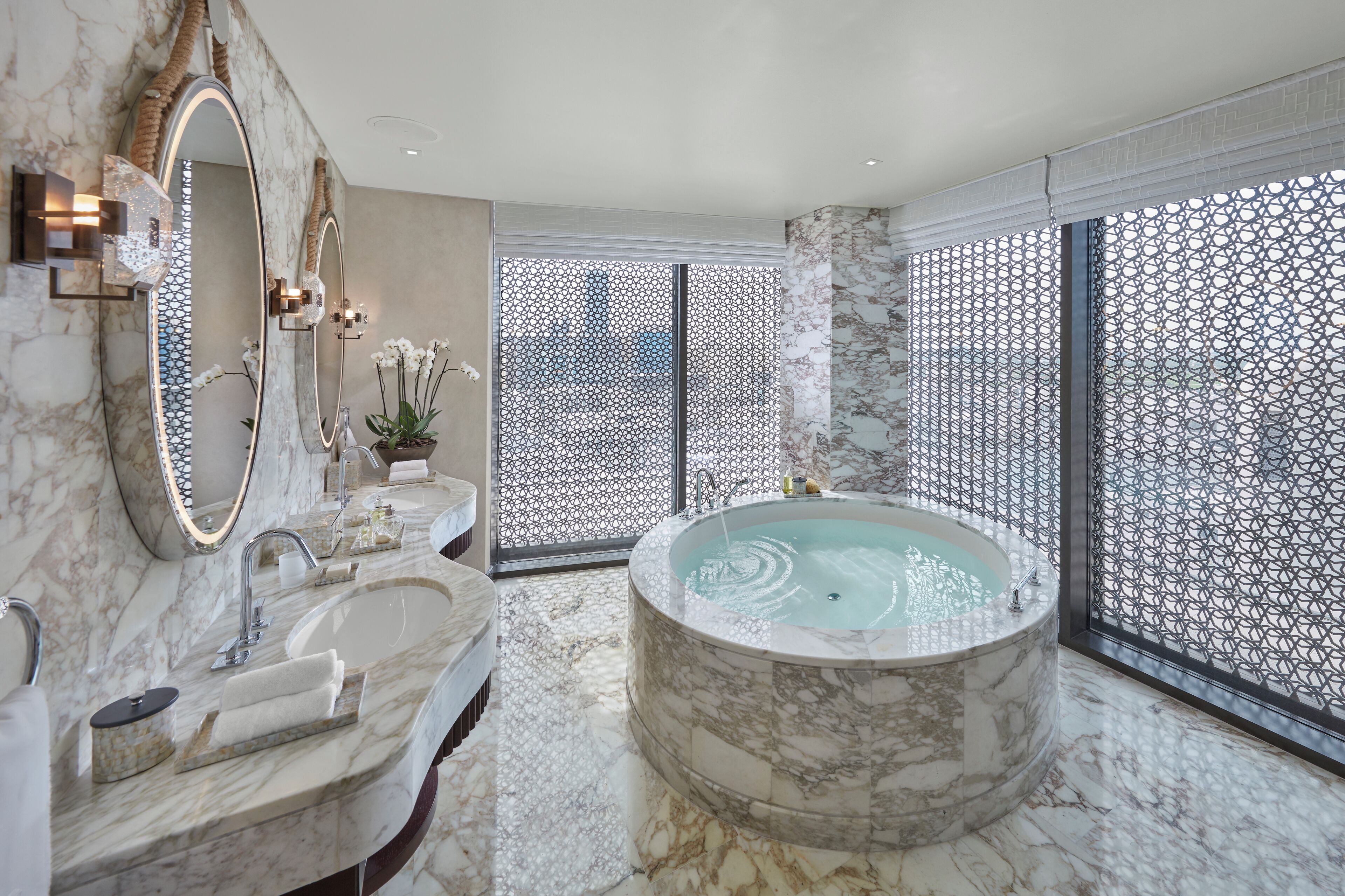 A luxurious bathroom with a marble sink, a large bathtub, and a decorative mirror.