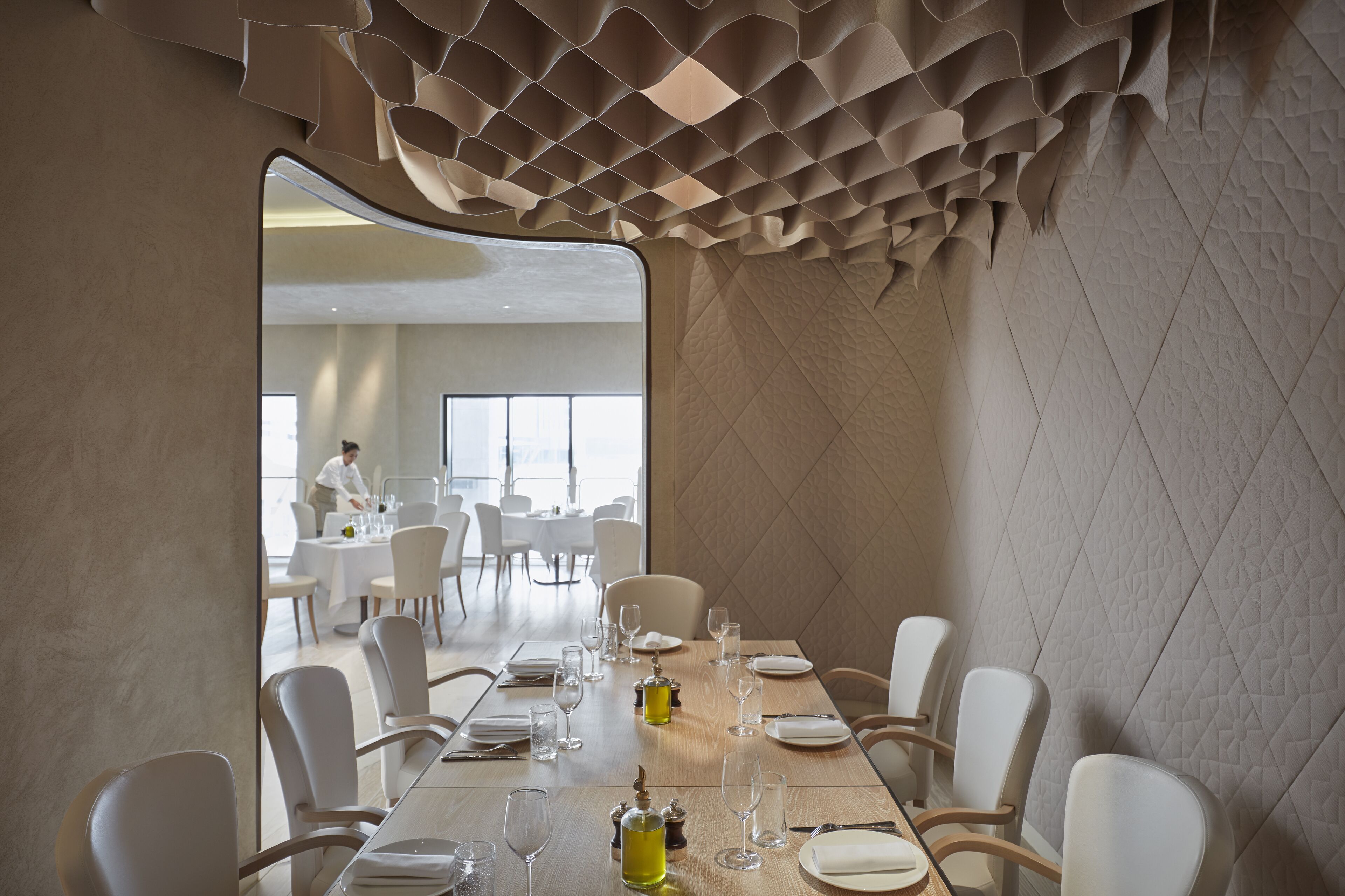 A dining area with a long table set for a meal, surrounded by chairs.