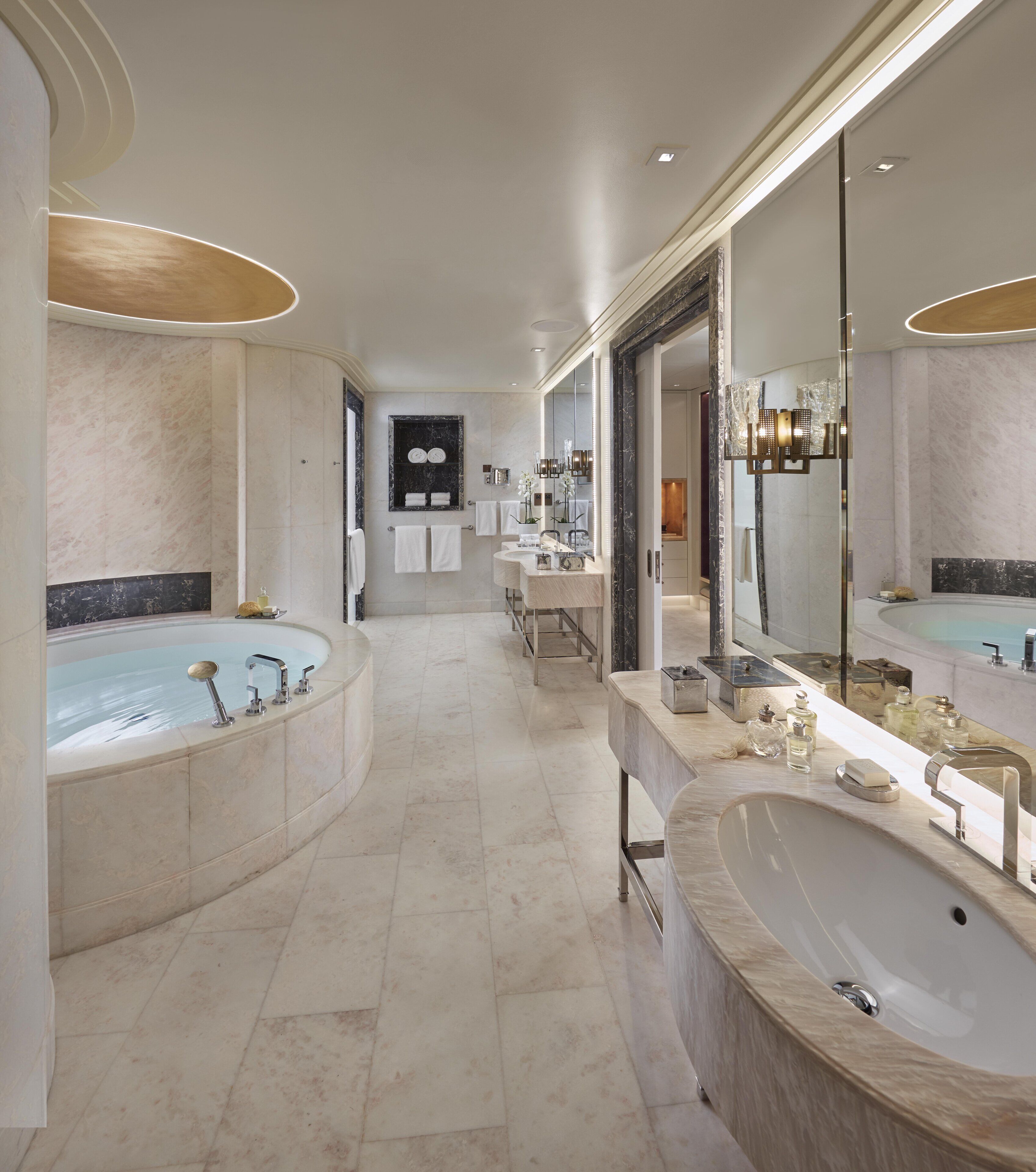 Een ruime badkamer met een groot bad, een apart wastafelmeubel en een make-up ruimte.