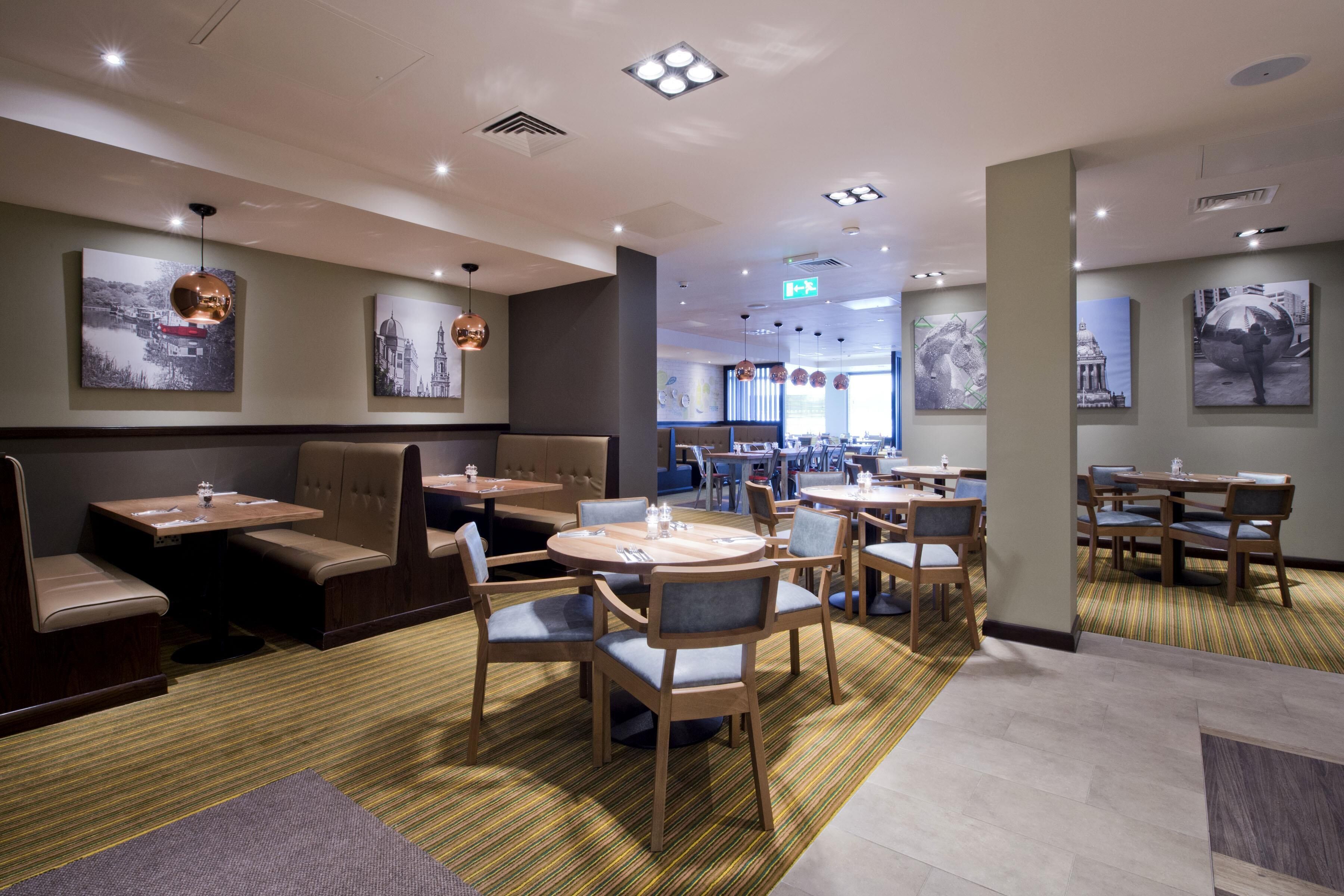 A restaurant with booths and tables, ceiling lights, and artwork on the walls.