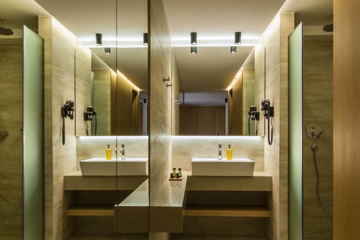 A modern bathroom with two sinks, mirrors, and a shower area.