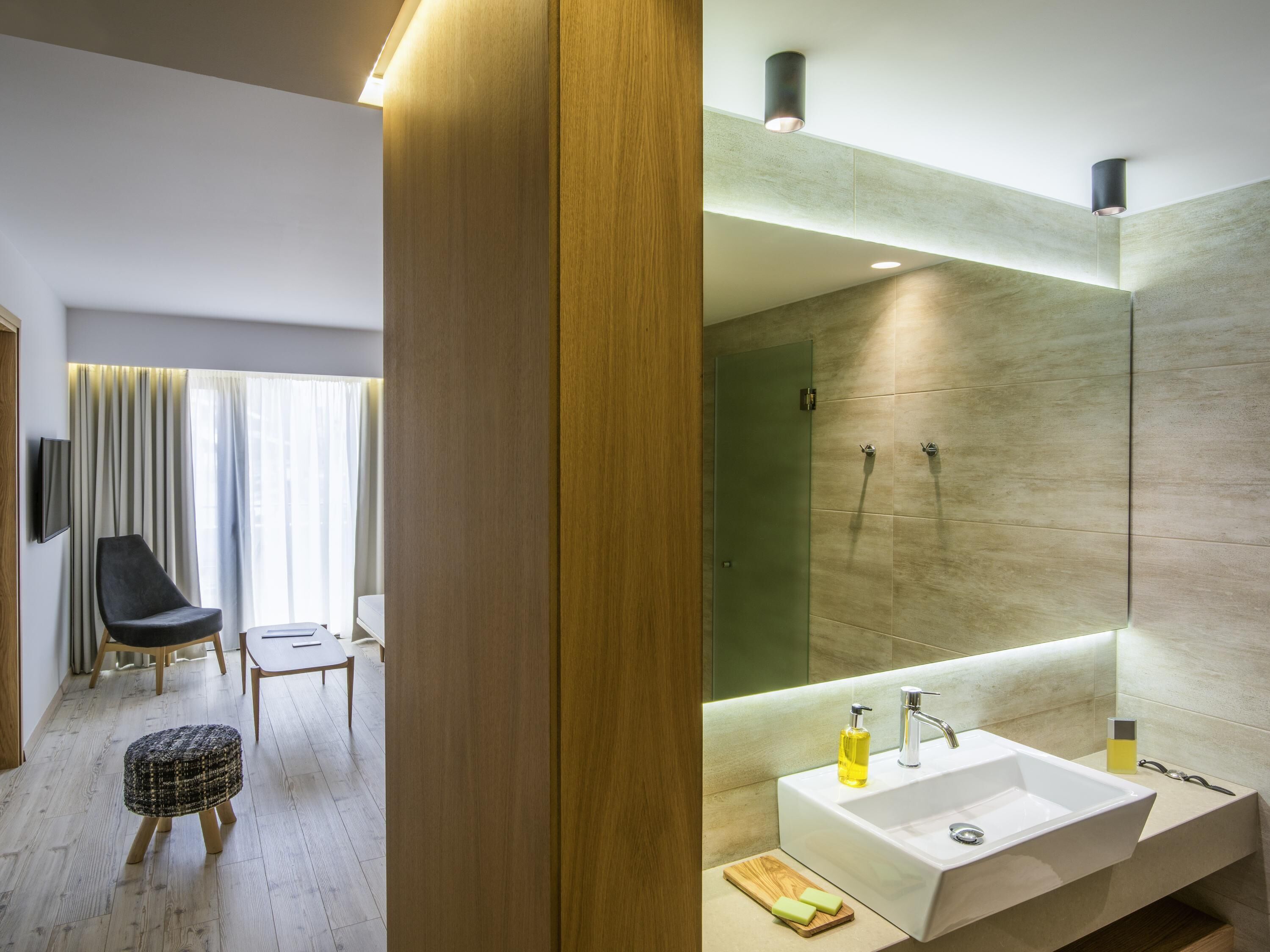 Un baño moderno con un espejo grande, un lavabo blanco y una zona de ducha.