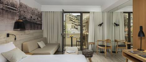 Habitación de hotel con cama, sofá, escritorio y vista del paisaje urbano a través de la ventana.