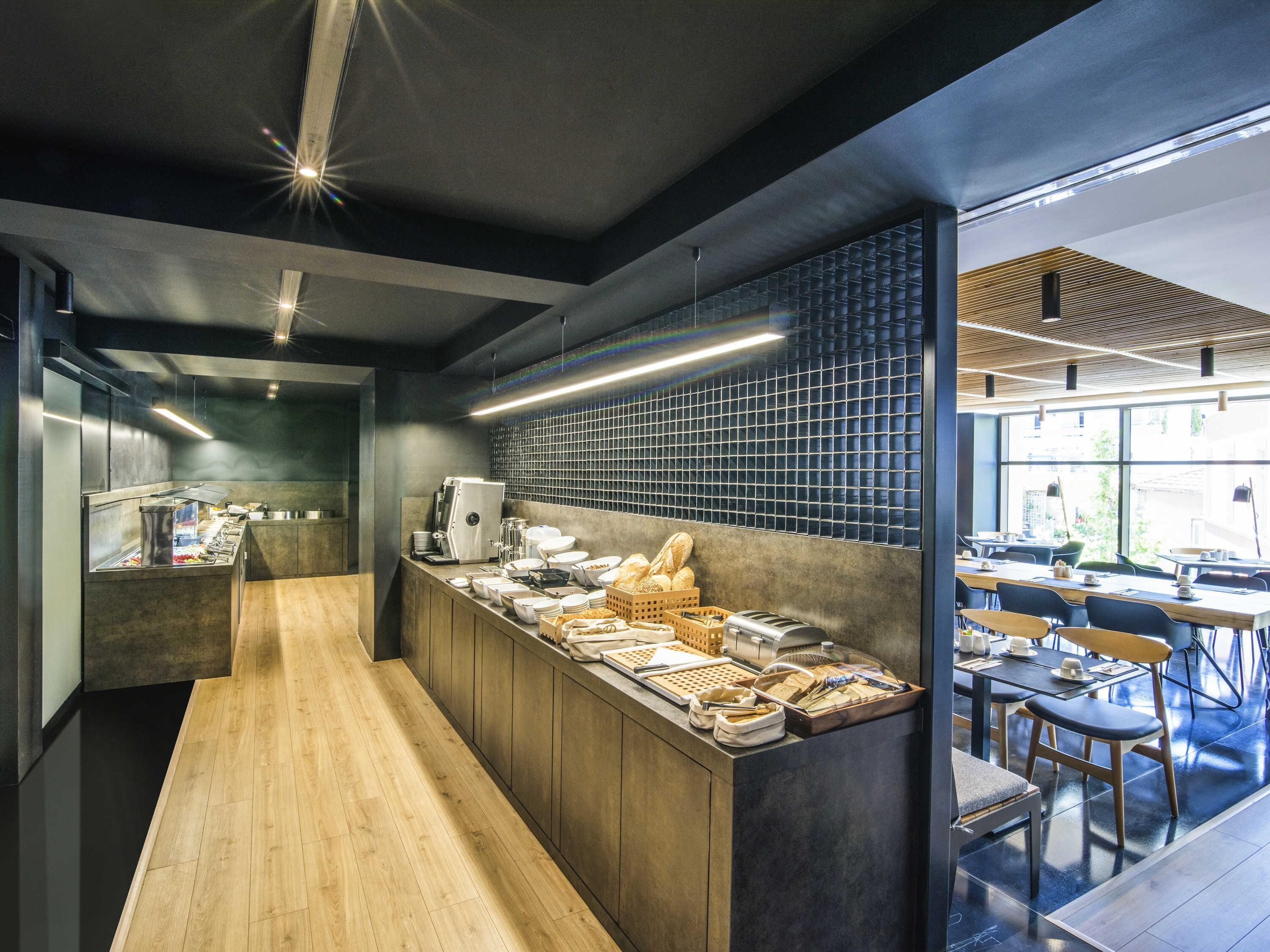 A modern cafe with a long counter, seating area, and large windows.