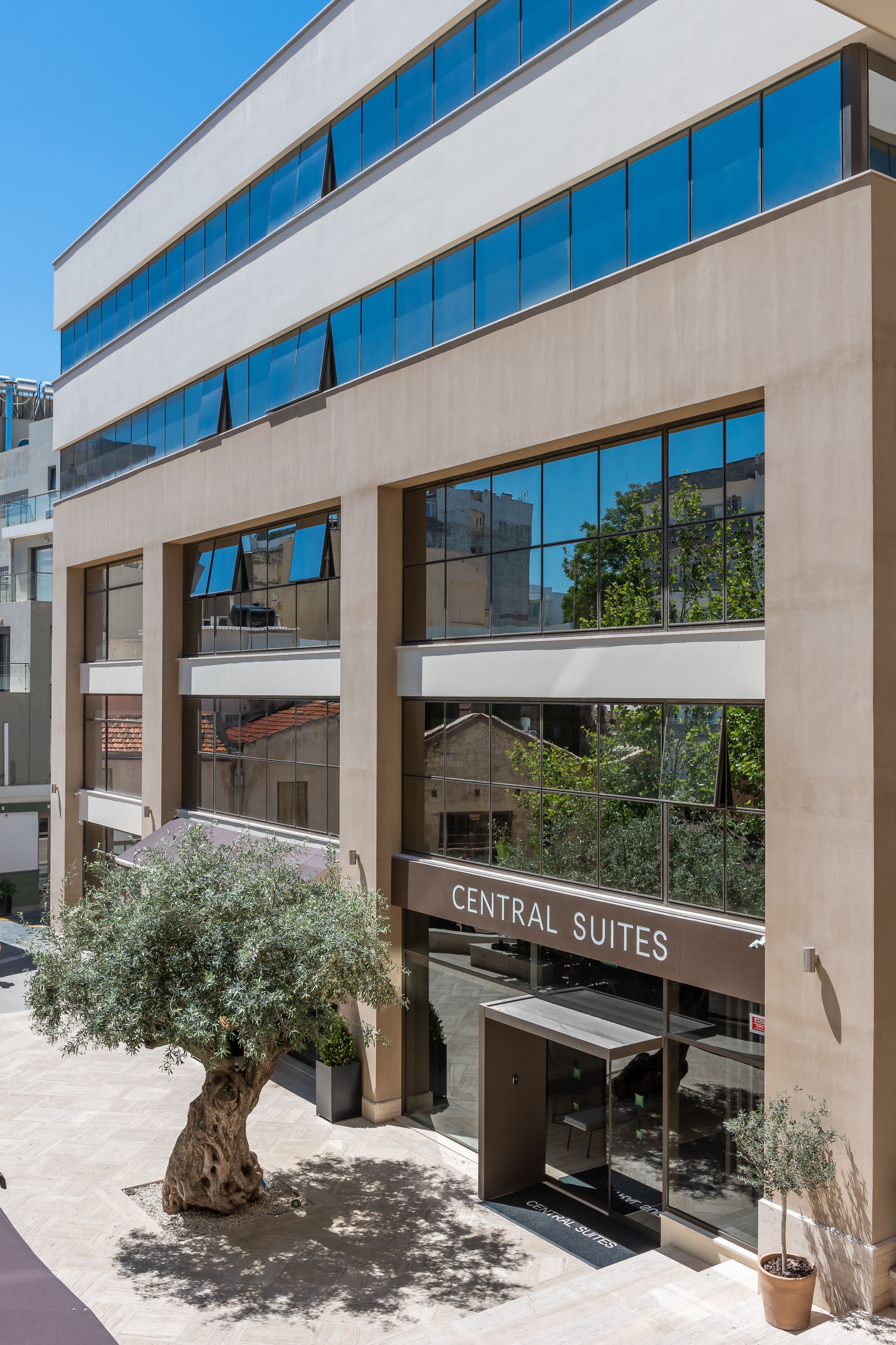 A modern building with multiple floors, large windows, and a sign reading "Central Suites".