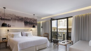 Una habitación de hotel moderna con una cama grande, una mesita, un sofá y un balcón con cortinas.