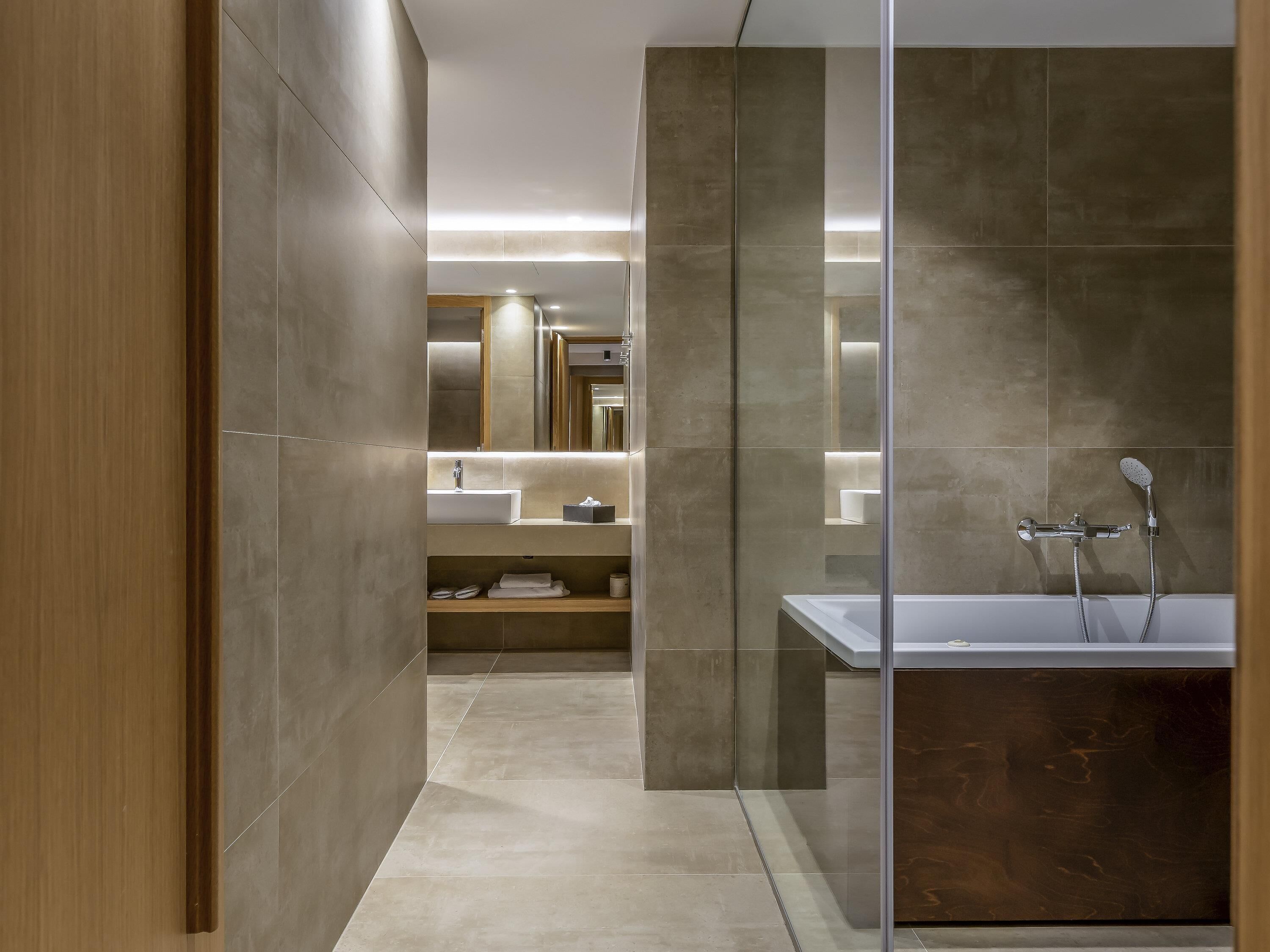 A modern bathroom with a glass partition, a sink, a shower, and a mirror.