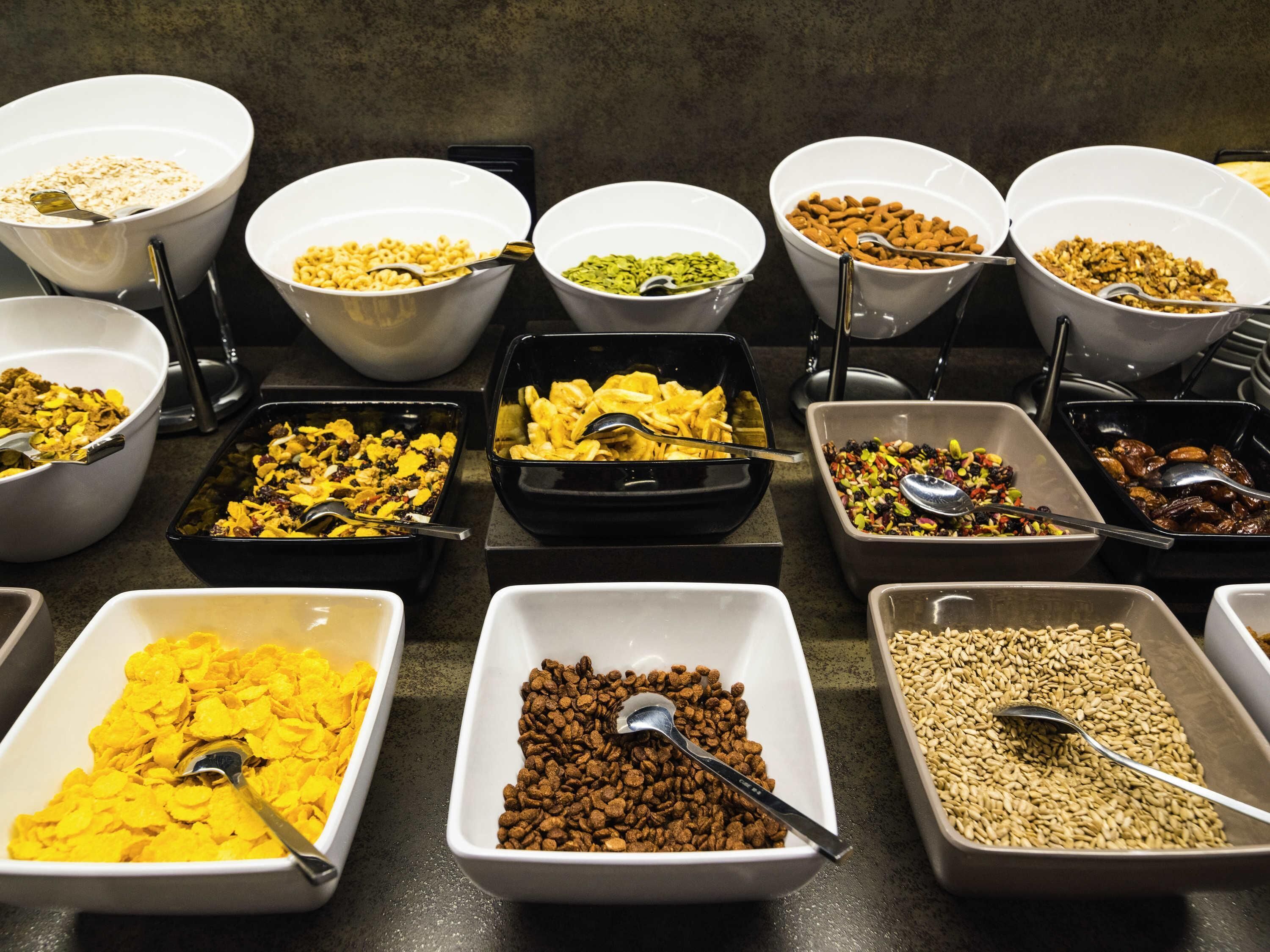 Diversas opciones de alimentos en cuencos y bandejas, como cereales, nueces y frutas secas.